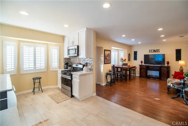 a kitchen with stainless steel appliances granite countertop a refrigerator and a dining table chair