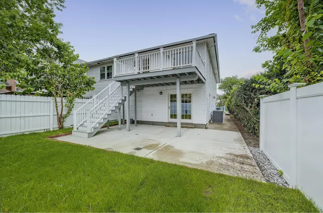 a view of a house with a yard plants and large tree