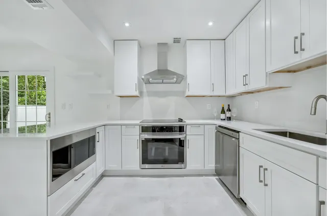 a kitchen with stainless steel appliances a refrigerator sink and white cabinets