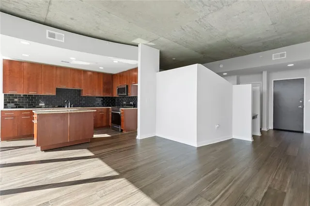 a kitchen with stainless steel appliances kitchen island granite countertop a refrigerator a sink and a wooden cabinets