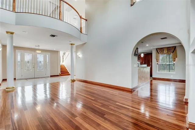 a view of an empty room with wooden floor and a chandelier