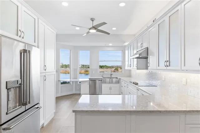 a kitchen with stainless steel appliances granite countertop a refrigerator a sink and white cabinets