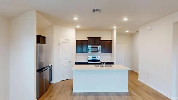 a room with kitchen island stainless steel appliances a refrigerator a stove top oven a sink and dishwasher