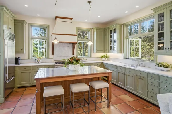 a kitchen with a dining table chairs cabinets wooden floor and appliances