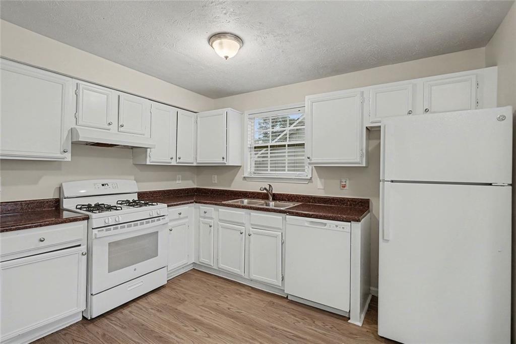 5571 Tunbridge Wells Road Lithonia, GA 30058 - Photo 8 of 23 a kitchen with granite countertop white cabinets and white appliances