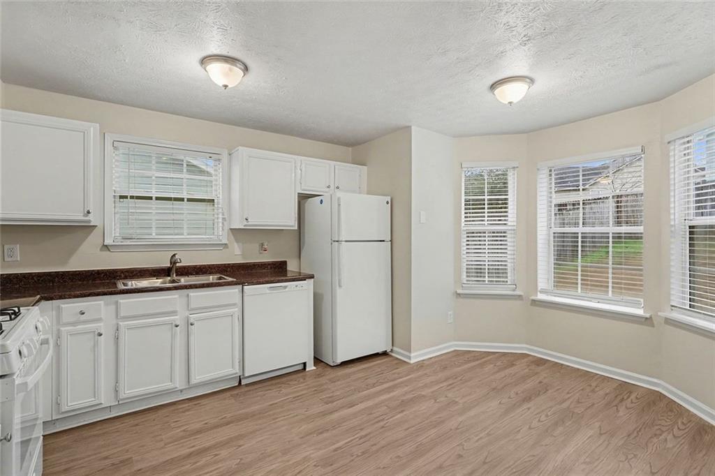 5571 Tunbridge Wells Road Lithonia, GA 30058 - Photo 9 of 23 a kitchen with granite countertop white cabinets and white appliances