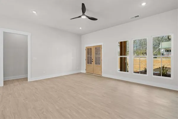 a view of an empty room with a window and chandelier fan