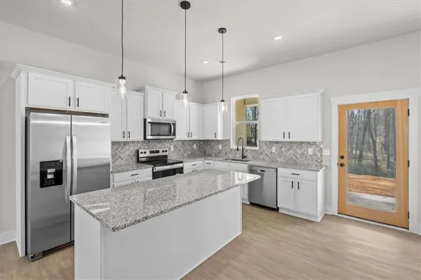 a kitchen with stainless steel appliances granite countertop a sink a stove a refrigerator a center island and cabinets