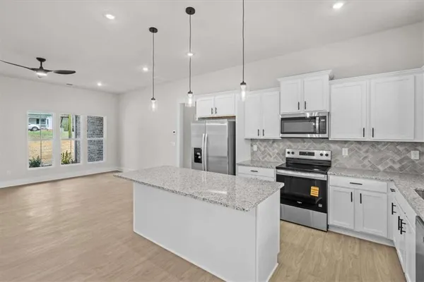 a large kitchen with stainless steel appliances granite countertop a stove a sink a refrigerator a center island with wooden floor and cabinets