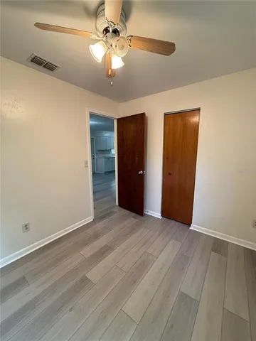 an empty room with closet and a ceiling fan