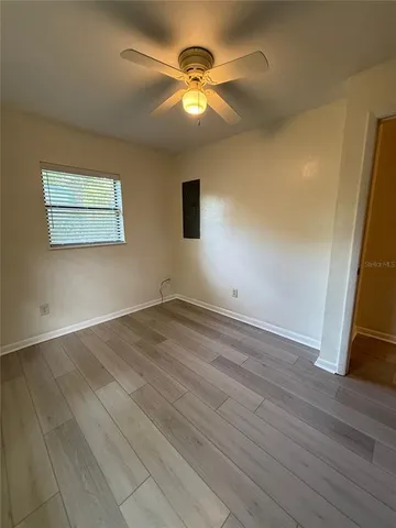 an empty room with wooden floor and a ceiling fan