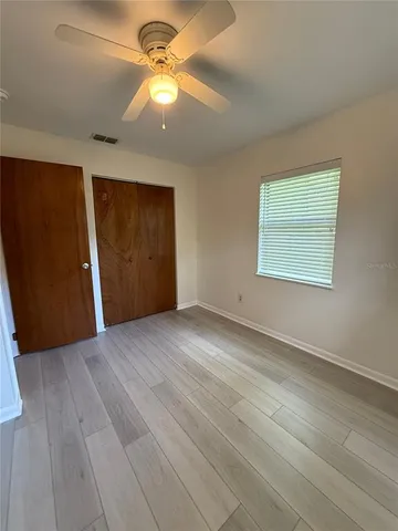 an empty room with windows and fan