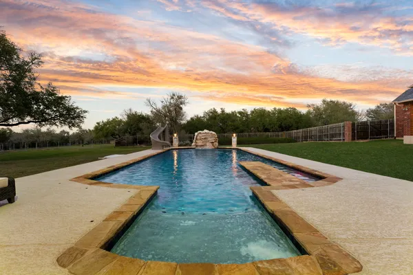 swimming pool with seating space and trees in the background