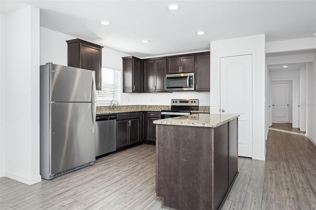 8646 Pinetop Ridge Lane Brooksville, FL 34613 - Photo 11 of 76 a kitchen with stainless steel appliances granite countertop a refrigerator a stove top oven a sink and dishwasher with wooden floor