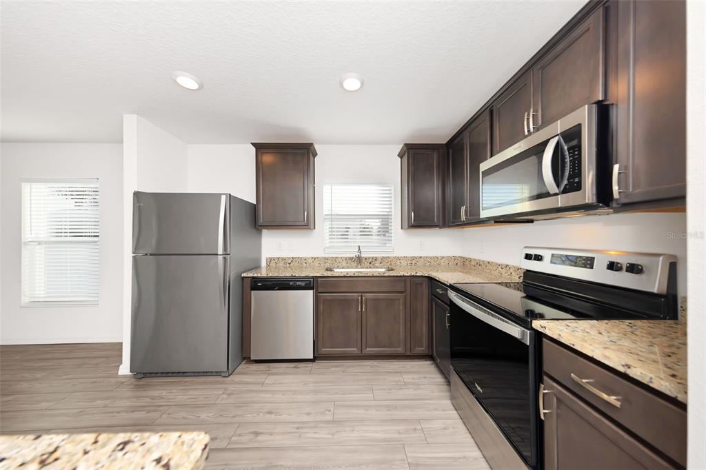 8646 Pinetop Ridge Lane Brooksville, FL 34613 - Photo 9 of 76 a kitchen with stainless steel appliances granite countertop a stove a refrigerator and a microwave