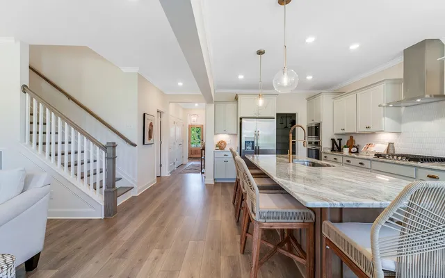 an open kitchen with wooden floor and chairs