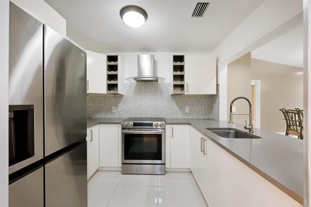 a kitchen with stainless steel appliances granite countertop a stove a sink and a refrigerator