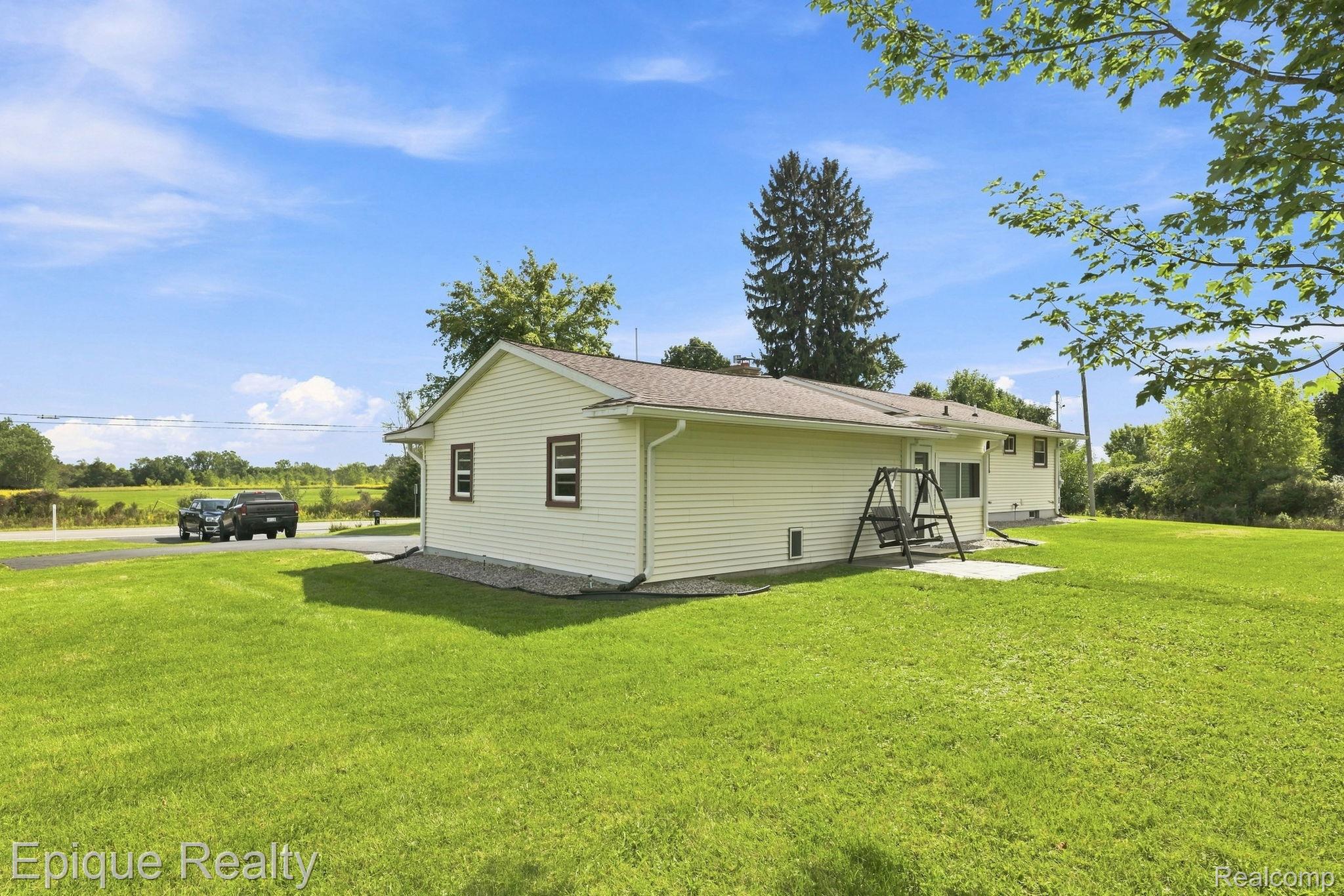 10091 North Genesee Road Mount Morris, MI 48458 - Photo 31 of 35 Expansive lawn surrounding the property, light-colored horizontal siding, dark-trimmed windows, and an outdoor concrete patio