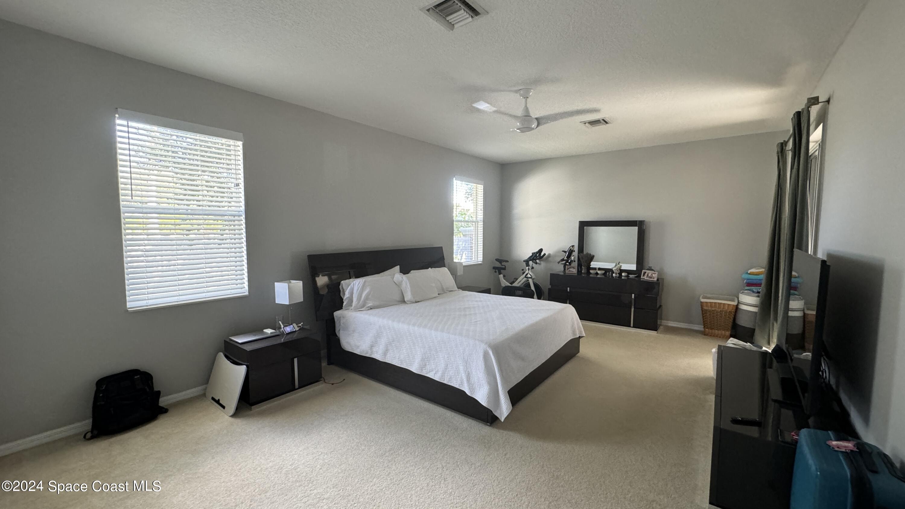 1471 Tamango Drive Melbourne, FL 32904 - Photo 5 of 23 a spacious bedroom with a bed and a flat tv screen on a dresser