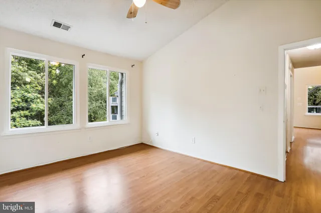 an empty room with wooden floor and windows