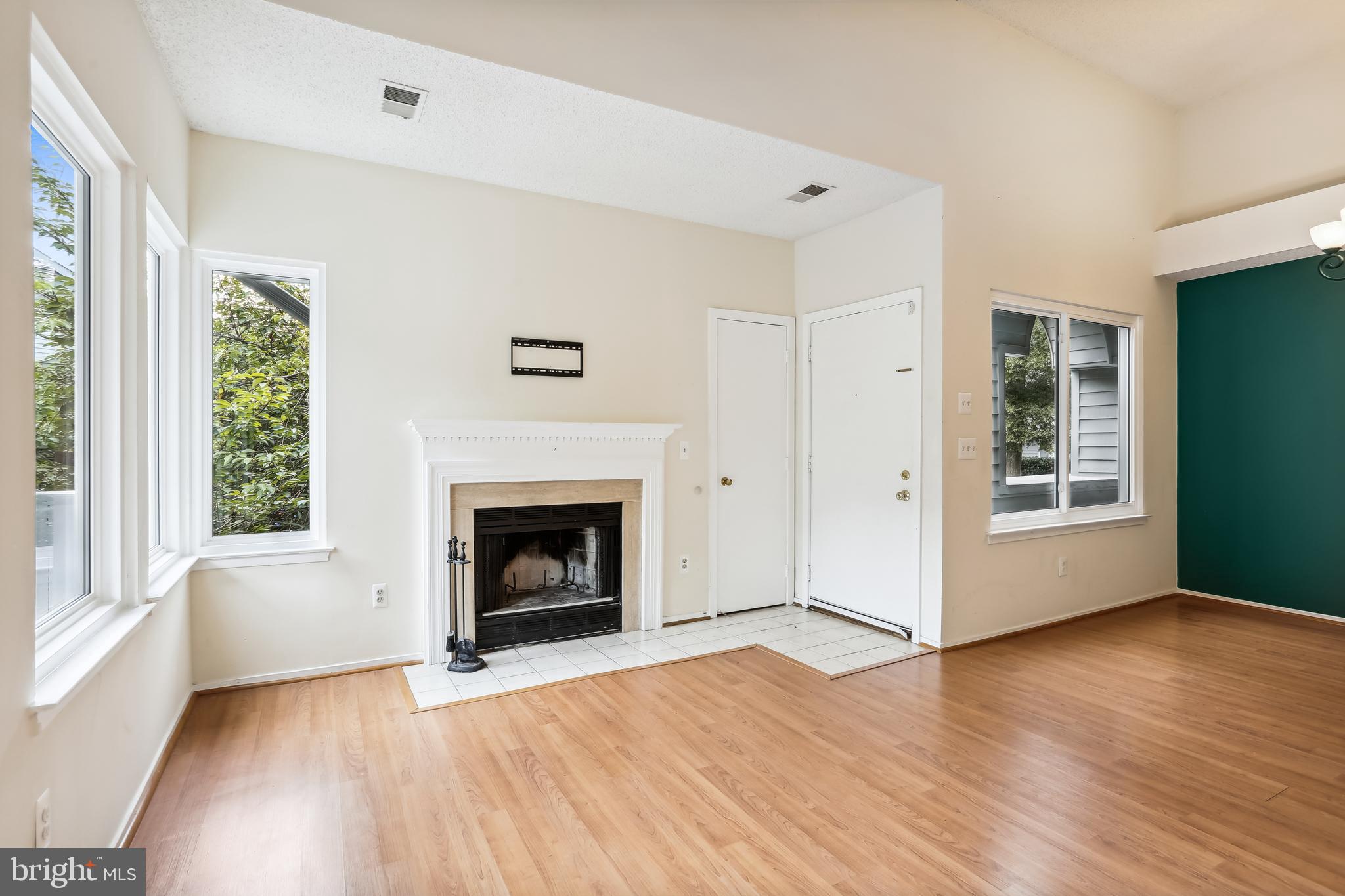 11719 E Summerchase Circle, Unit 1719E Reston, VA 20194 - Photo 7 of 26 an empty room with wooden floor fireplace and windows