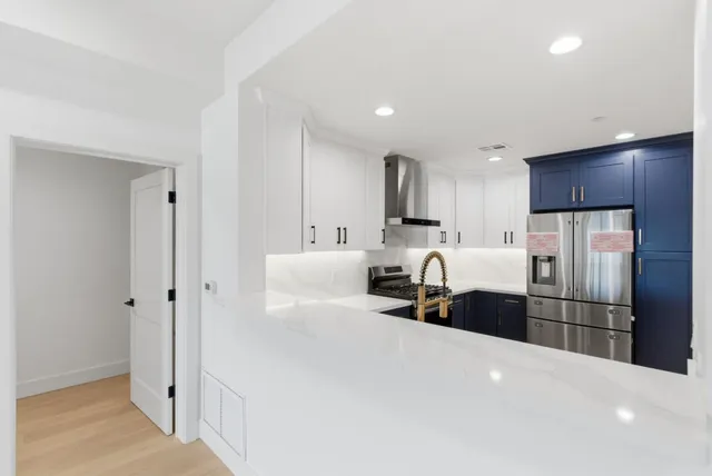 a large white kitchen with kitchen island a sink a stove and a refrigerator
