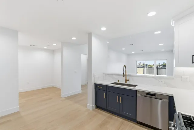 a kitchen with kitchen island granite countertop a sink and a refrigerator