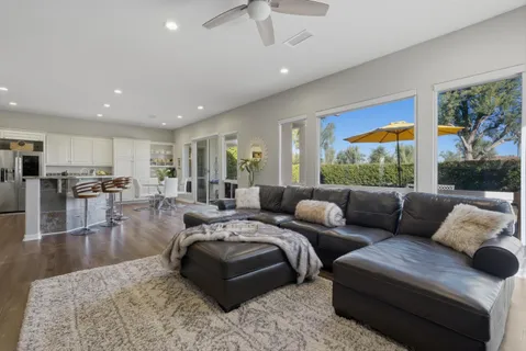 a kitchen with stainless steel appliances kitchen island granite countertop a stove a sink a refrigerator and white cabinets with wooden floor