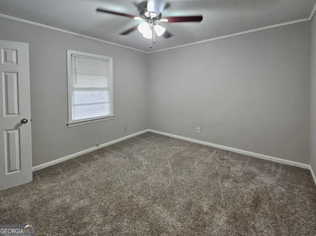 an empty room with a chandelier fan and windows