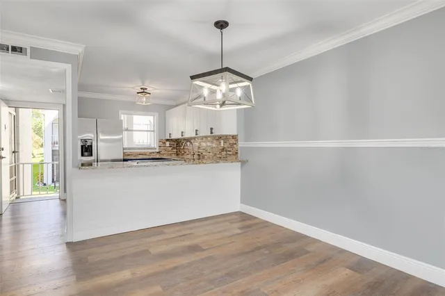 a view of a kitchen with wooden floor and stainless steel appliances