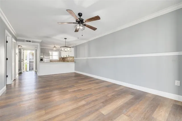 a view of a kitchen with a sink a refrigerator a ceiling fan and wooden floor