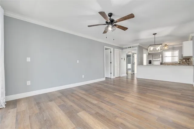 a view of a livingroom with a ceiling fan wooden floor and a ceiling fan