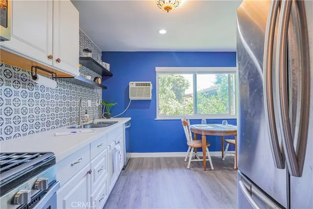 a kitchen with stainless steel appliances granite countertop a refrigerator a sink dishwasher a stove and white countertops with wooden floor