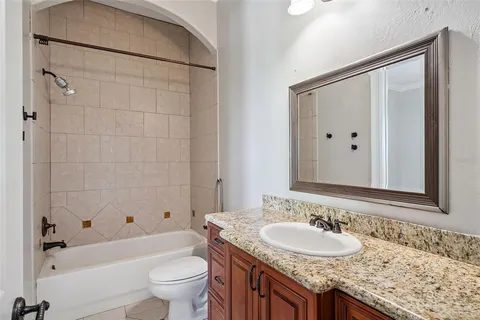 a bathroom with a granite countertop sink a toilet a mirror a bathtub and shower