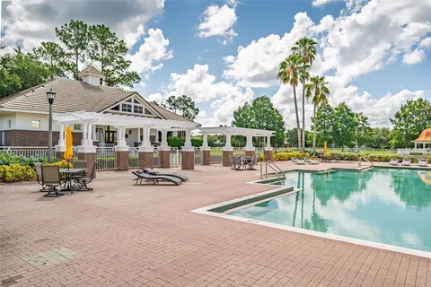 a view of a swimming pool with lawn chairs and plants