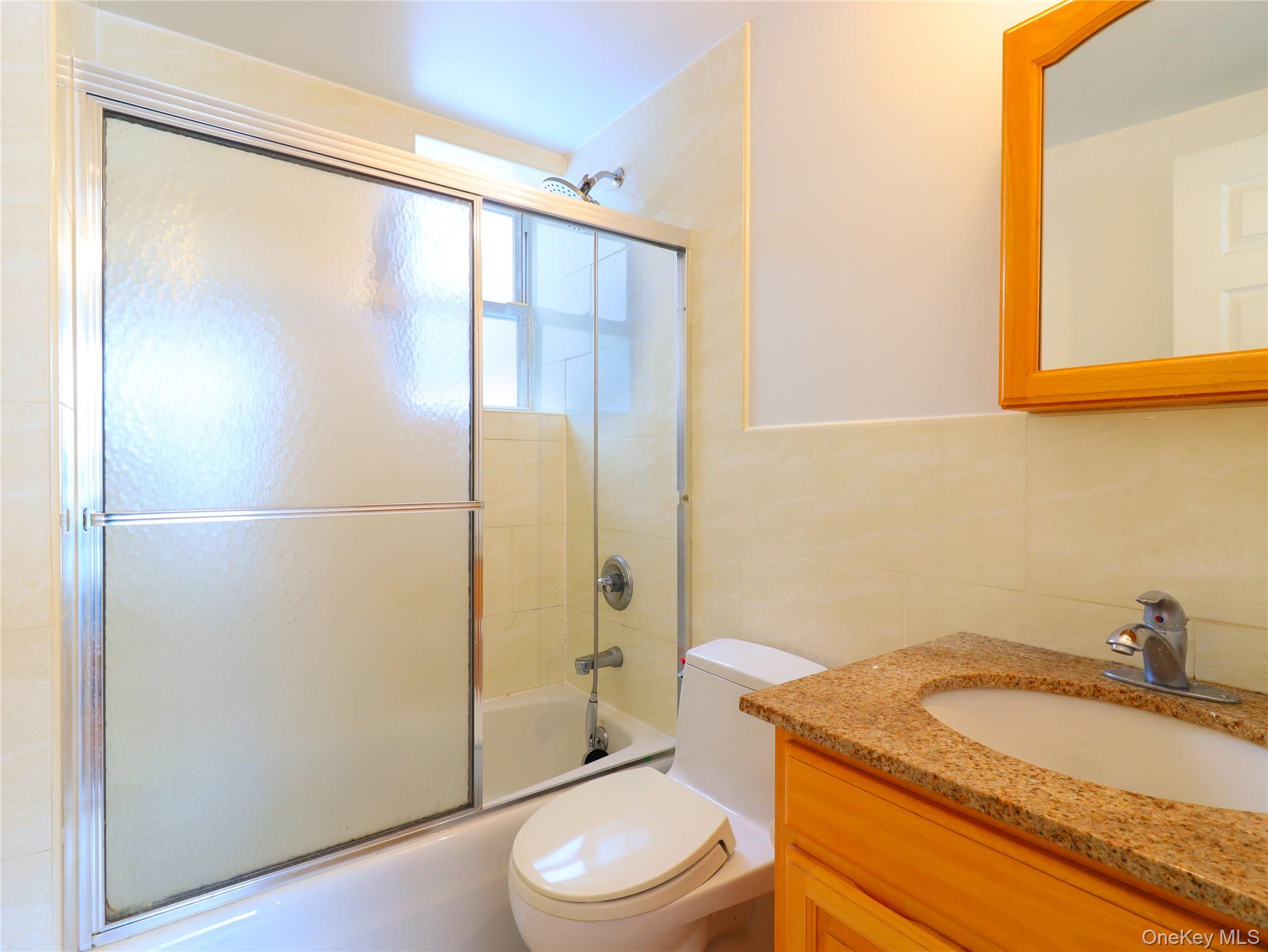 137-08 31st Road, Unit 5E Queens, NY 11354 - Photo 12 of 14 a bathroom with a granite countertop sink toilet and shower