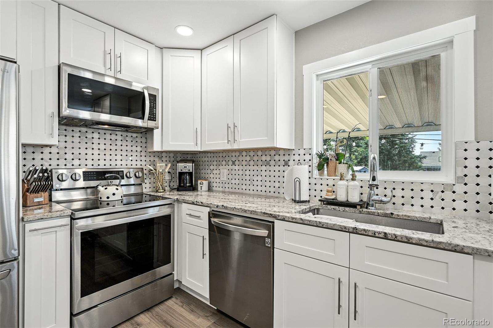 2714 South Raleigh Street Denver, CO 80236 - Photo 11 of 34 a kitchen with granite countertop white cabinets stainless steel appliances a sink and a window