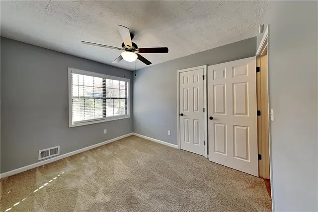 an empty room with windows and fan