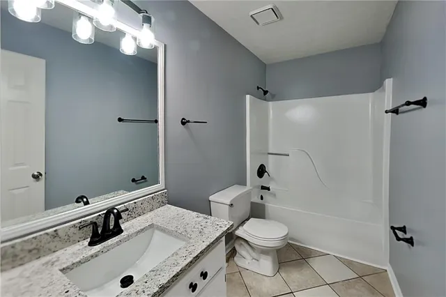 a bathroom with a granite countertop sink toilet a large mirror a shower and a mirror