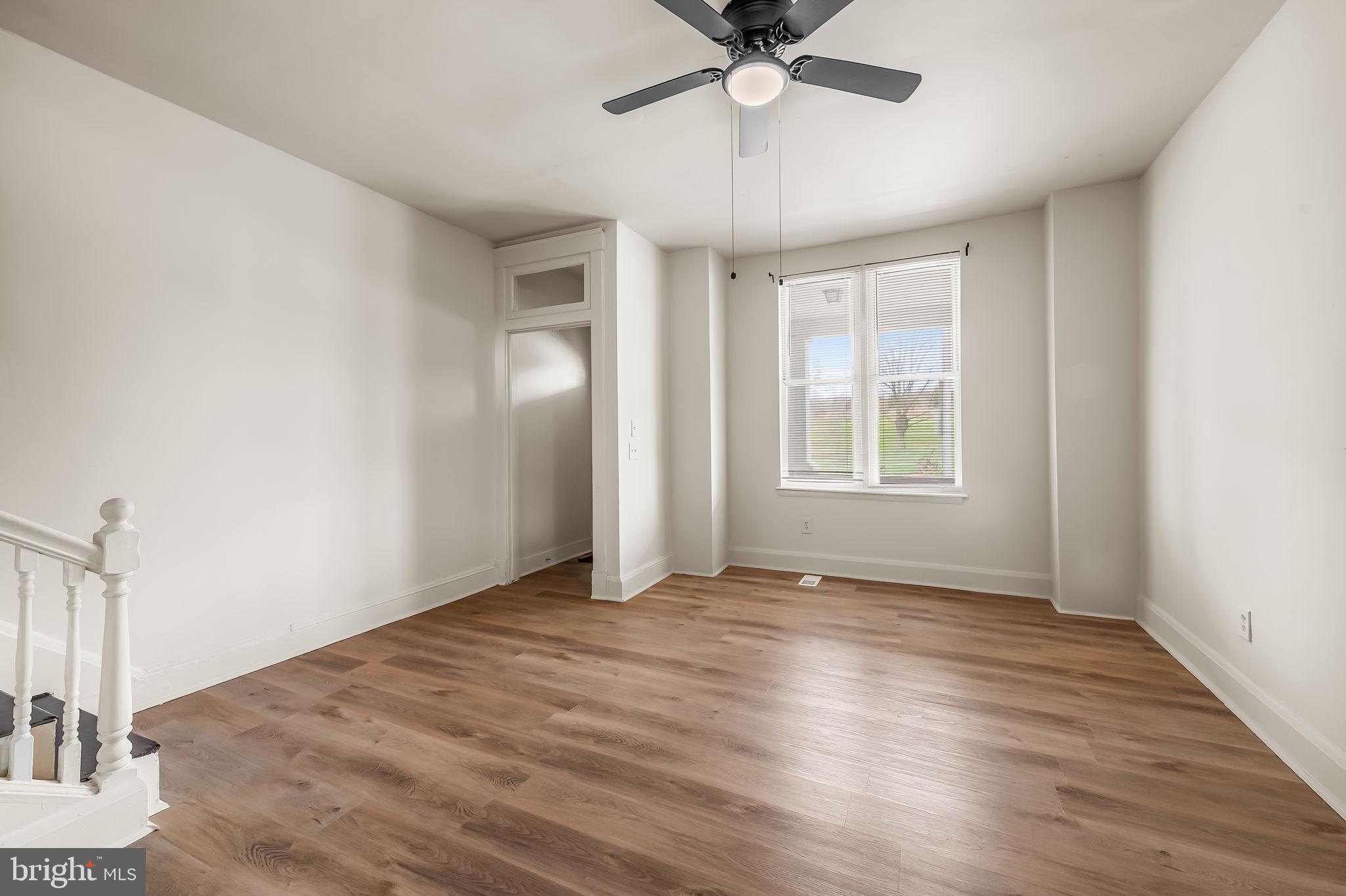3021 Belair Road Baltimore, MD 21213 - Photo 4 of 27 an empty room with wooden floor fan and windows