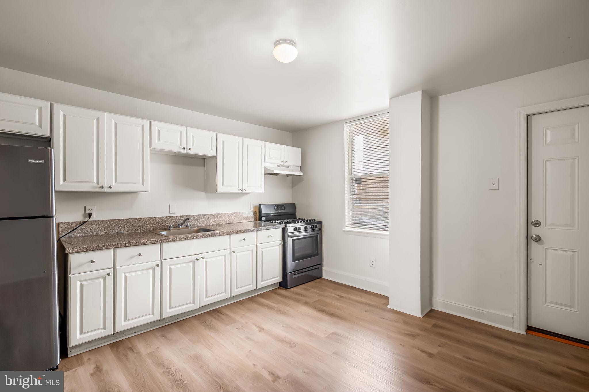 3021 Belair Road Baltimore, MD 21213 - Photo 10 of 27 a kitchen with stainless steel appliances granite countertop a stove top oven a sink and dishwasher with wooden floor