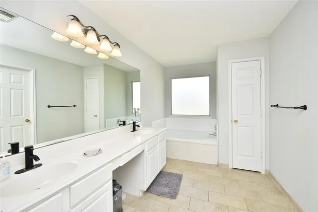 a spacious bathroom with a tub sink and mirror