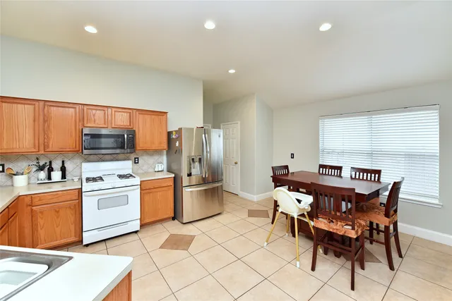 a kitchen with stainless steel appliances a stove a sink a refrigerator a dining table and chairs