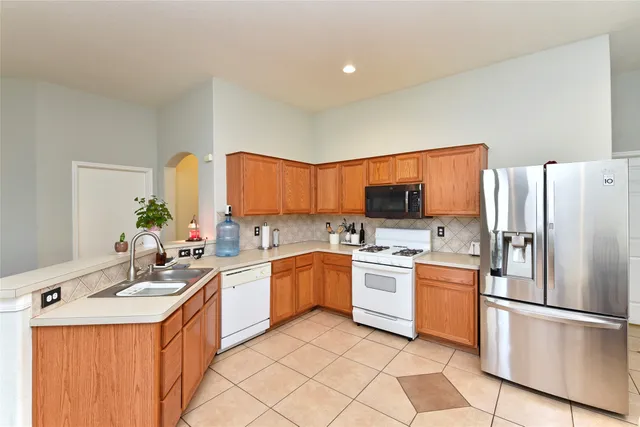 a kitchen with a sink a refrigerator and a stove top oven