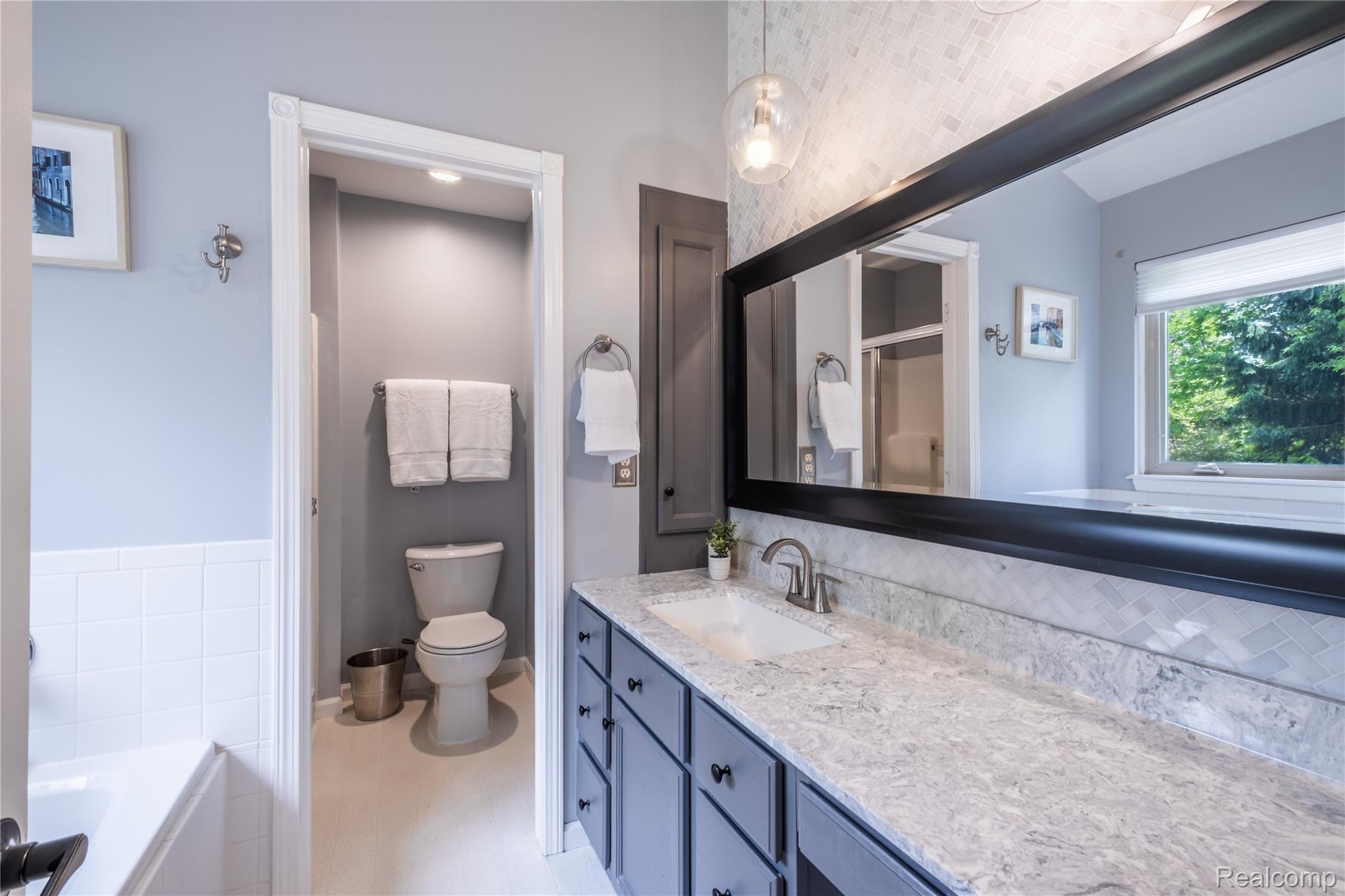 Bathroom vanity featuring a single undermount sink, a light-toned countertop, and dark cabinetry