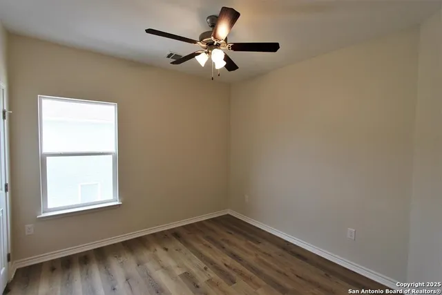 a a room with wooden floor and ceiling fan
