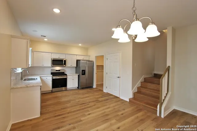 a kitchen with stainless steel appliances granite countertop a refrigerator a stove and a wooden floors