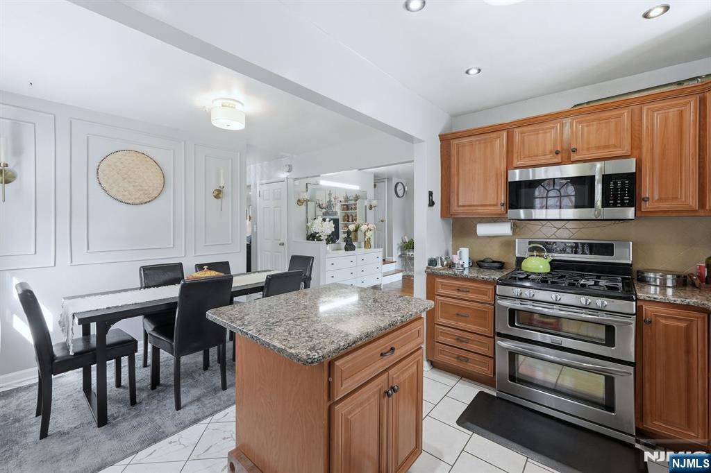 39 Voorhees Street Teaneck, NJ 07666 - Photo 10 of 47 a kitchen with granite countertop a stove top oven microwave and cabinets