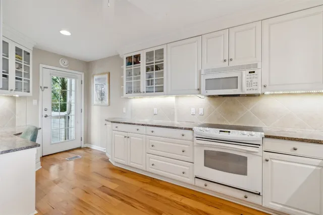 a kitchen with granite countertop white cabinets and white appliances