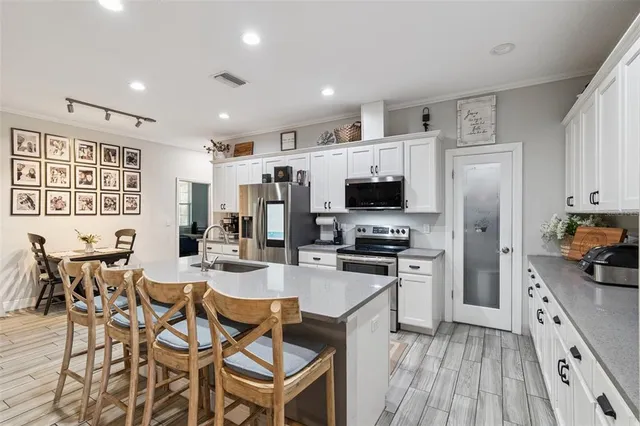 a kitchen with stainless steel appliances a stove top oven a refrigerator a sink dishwasher and a dining table with wooden floor